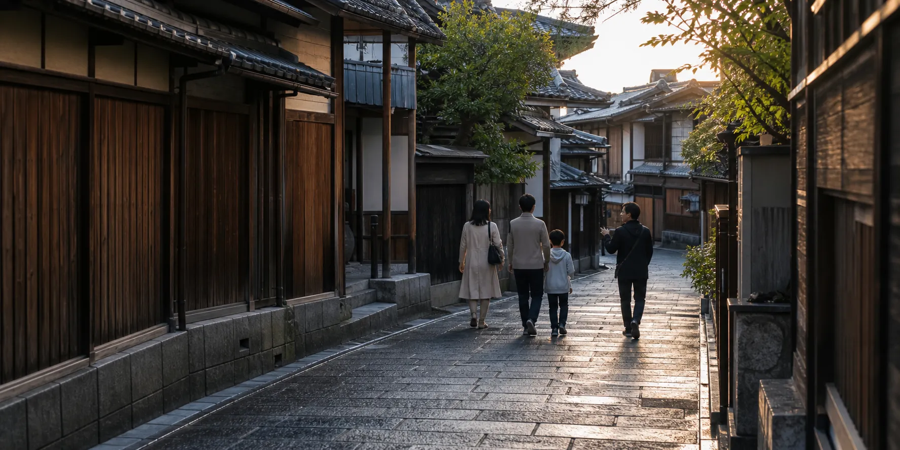 A quiet Kyoto stone lane in the early morning, with a guide walking behind a small family.